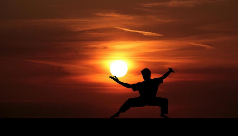 Kung Fu Praktizierender vor aufgehender Sonne.
