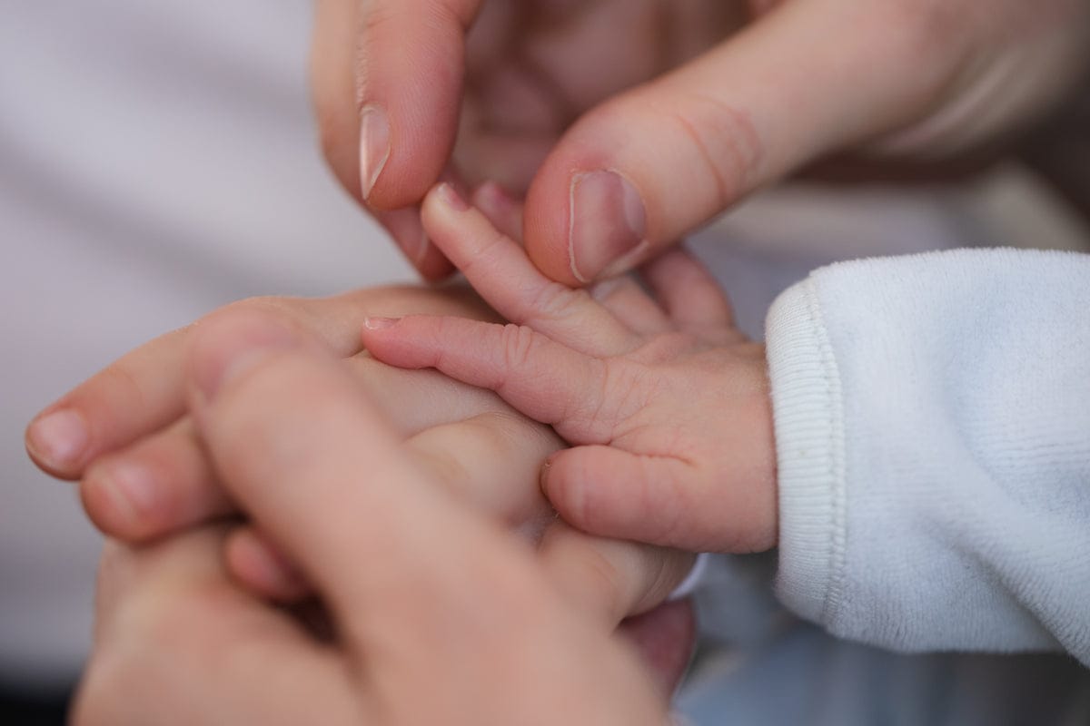 Eltern halten die Hand ihres Babys — Berührung, die Vertrauen schenkt