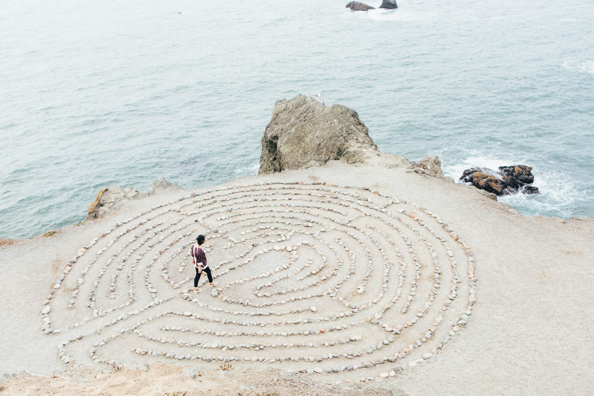 Sandlabyrinth am Strand mit einem Menschen kurz vor Eirreichen der Mitte.